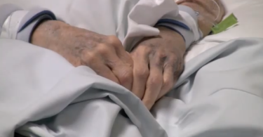 Patient's hands in hospital bed