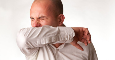 A man coughing into his sleeve