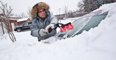 Man cleaning snow from car