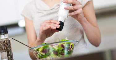 Woman putting salt on salad