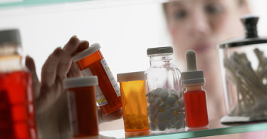 Woman taking pills from medicine cabinet