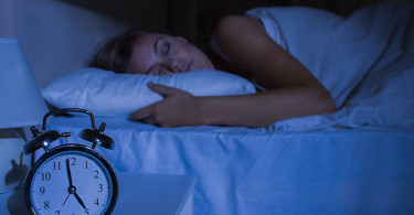 Focus on the alarm clock in front of sleeping woman