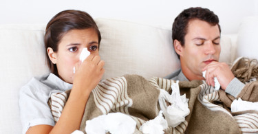 Young couple lie together in bed while they both have the flu