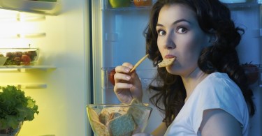 woman snacking at a fridge
