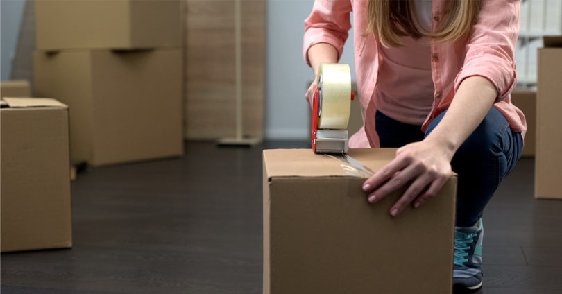 A woman tapes up a box in preparation for moving day.