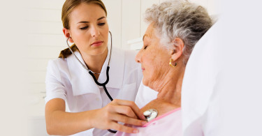 Nurse using stethoscope on patient