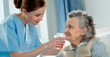 Elderly person getting fed by health care worker