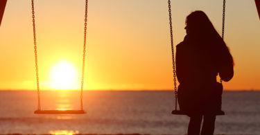 sihouette of woman on swingset