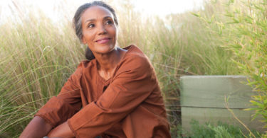 woman sitting in sunny field thinking