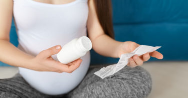 pregnant woman holding bottle of vitamins