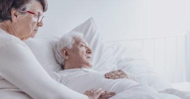 Elderly woman supporting sick husband