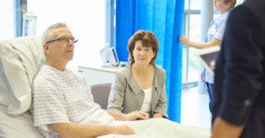 man in hospital bed with wife nearby