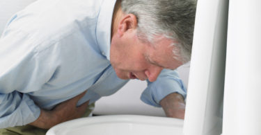 man leaning over toilet