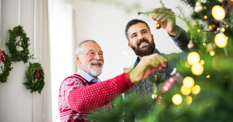 Adult son and father decorate Christmas tree