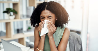 A woman blowing her nose in a napkin.