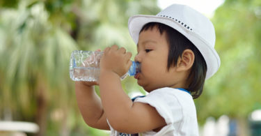 A baby drinks from a water bottle.