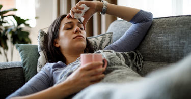 woman sick in bed with hand on her head