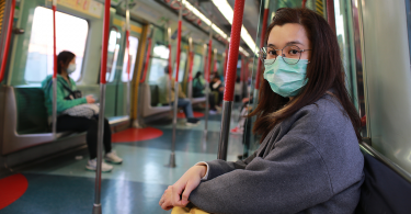 Woman wearing mask on public transit looking anxious
