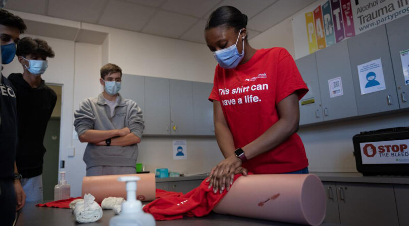 Christina Frimpong demonstrates how to stop a bleed on a silicon leg in front of students