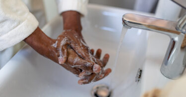 A woman is washing her hands with soap and water