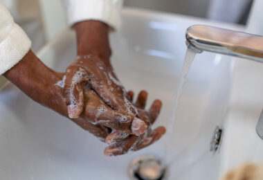 A woman is washing her hands with soap and water