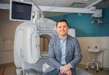 Dr. Alex Bilbily sitting in front of a CT scanner.